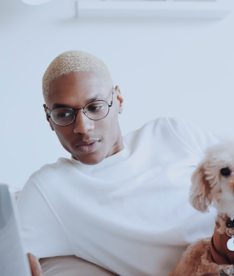 Imagem de um modelo de etinia negra, com cabelo descolorido e usando camiseta branca, junto de óculos de lente redonda e transparente